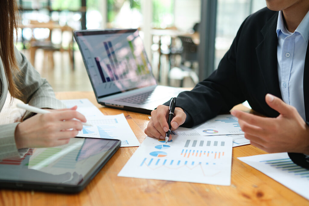 Two business people discuss investment strategy and collaborate with colleagues.